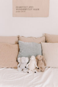 This image shows a "Fearfully and Wonderfully" made banner above a daybed with pillows and stuffed animals.
