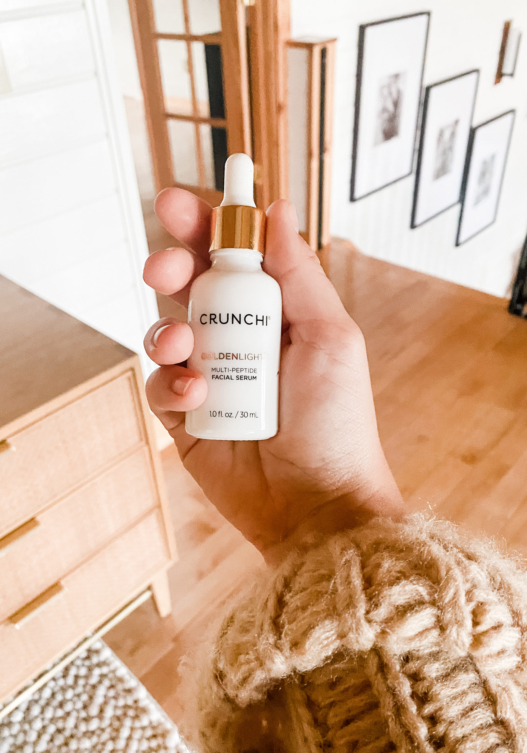 This image shows a hand holding Crunchi's Goldenlight serum, a skincare product that cna help transform your skin.