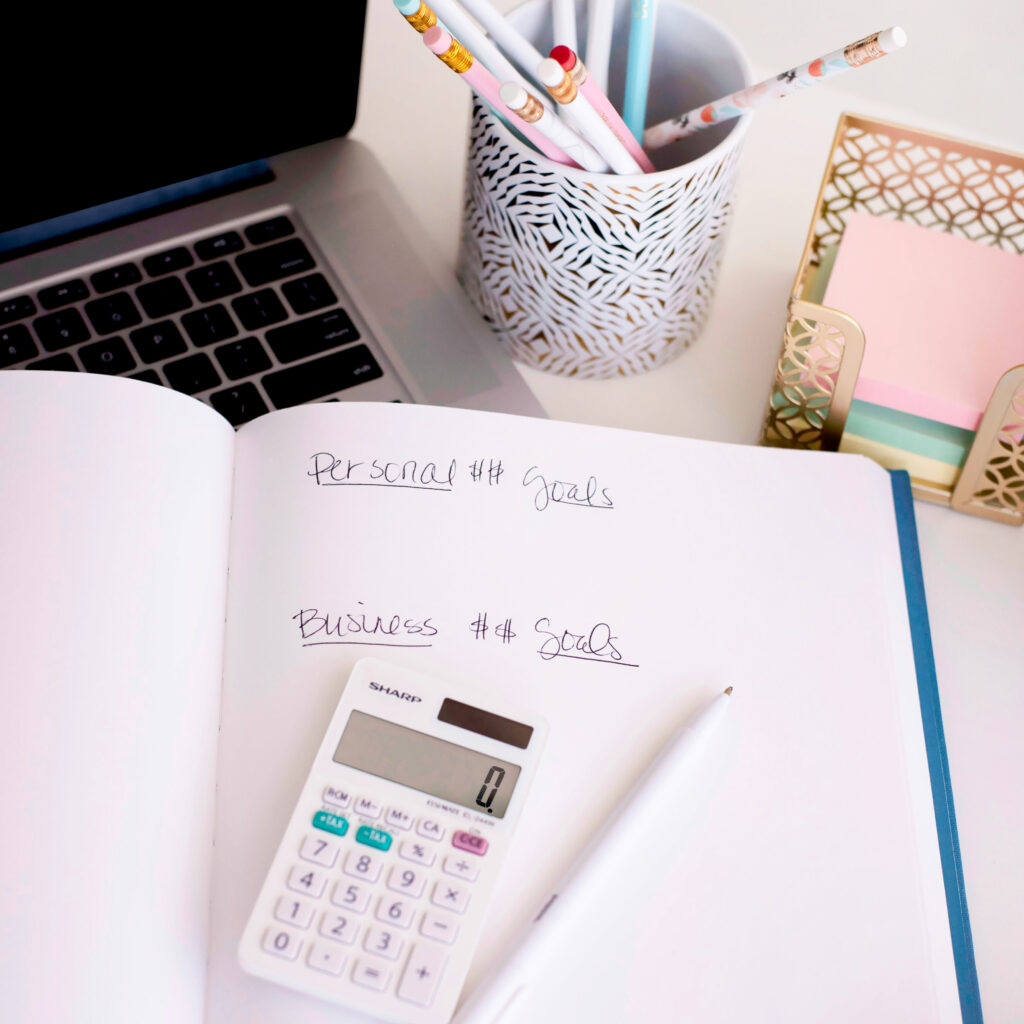 This image shows a calculator next to a notebook with financial goals.
