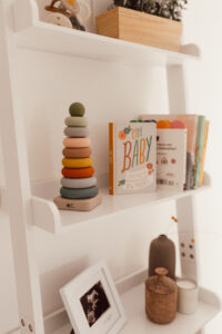 This image shows a white ladder shelf with books, a stacker toy, and an ultrasound photo.