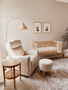 This image shows a gender neutral nursery with a crib, recliner, and bunny artwork.