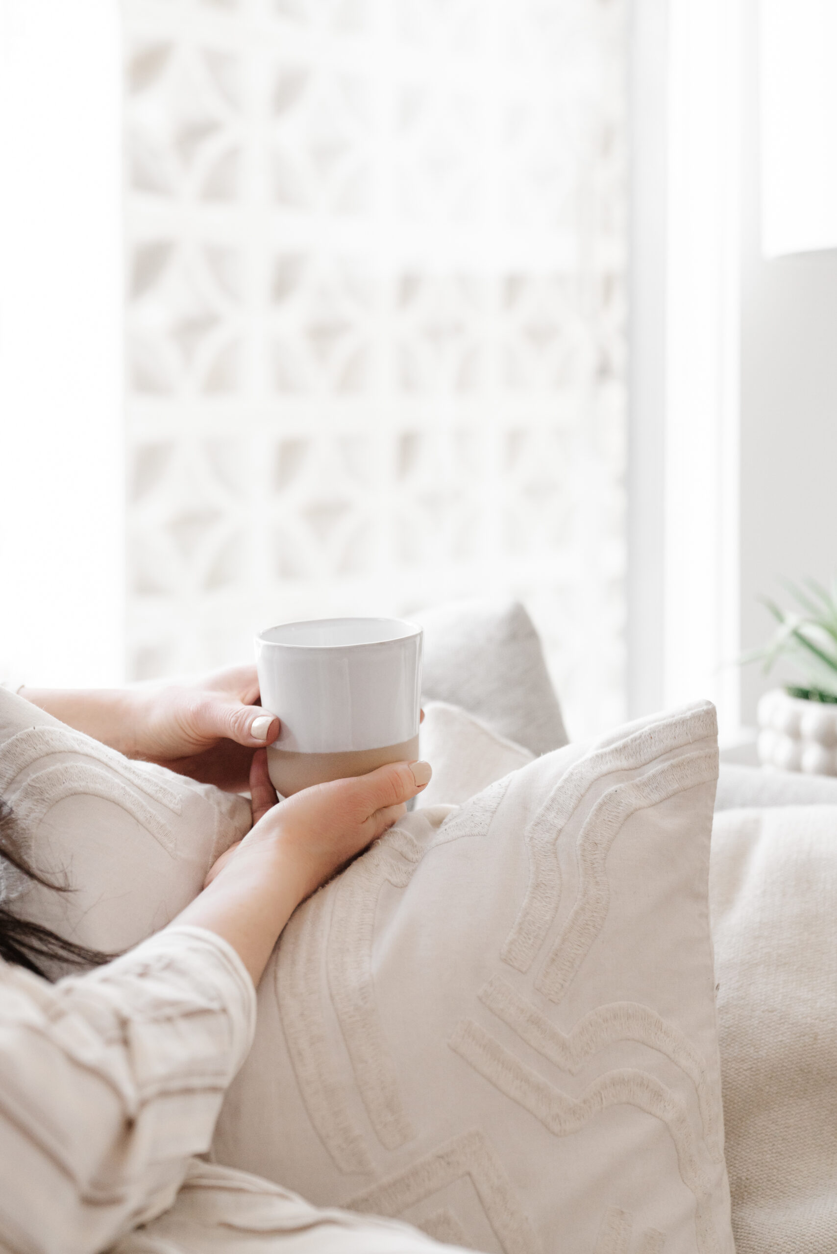 This image shows a woman holding a cup of coffee on a couch. In this episode, Jordan talks with author Jess Connolly about the importance of rest.