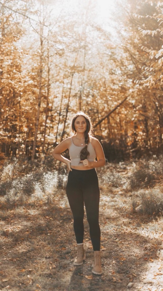 This image shows Jordan hiking through the forest, facing the camera and smiling.