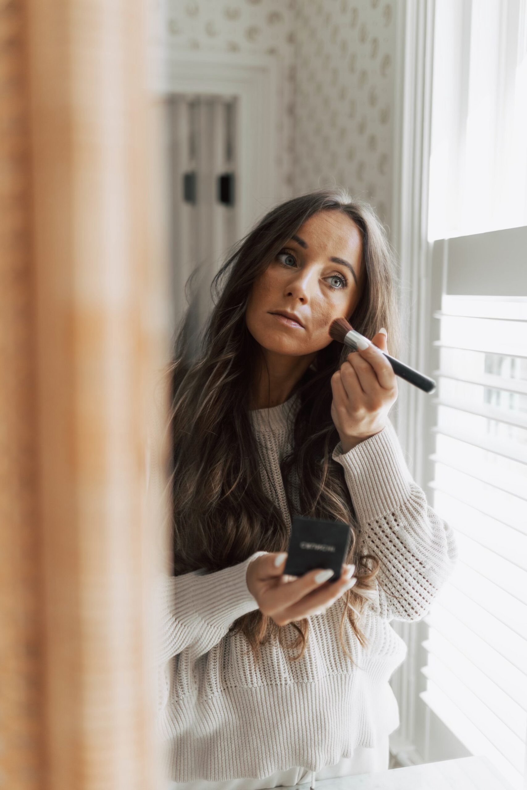 In this image, Jordan is looking at a mirror, applying makeup.