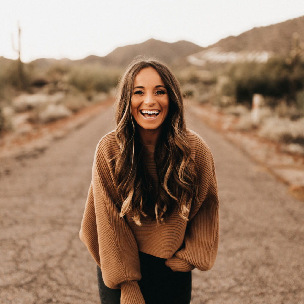 This image shows Jordan standing in the middle of a desert road, laughing at the camera.