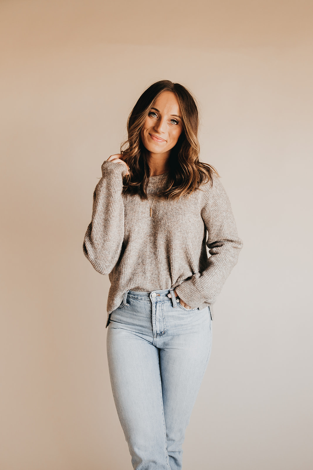 This image shows Jordan in a sweater and jeans, smiling at the camera. In this episode, Jordan talks about getting back to natural beauty in a world of unrealistic beauty standards.