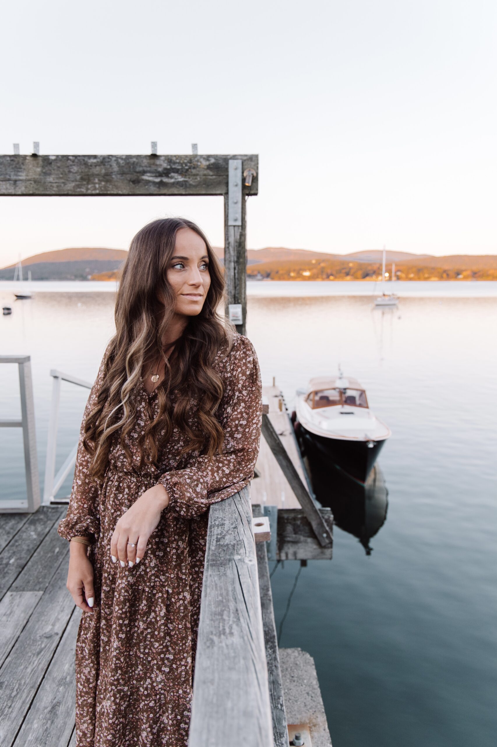 This image shows Jordan in a dress standing on a dock and looking to the right towards the water.