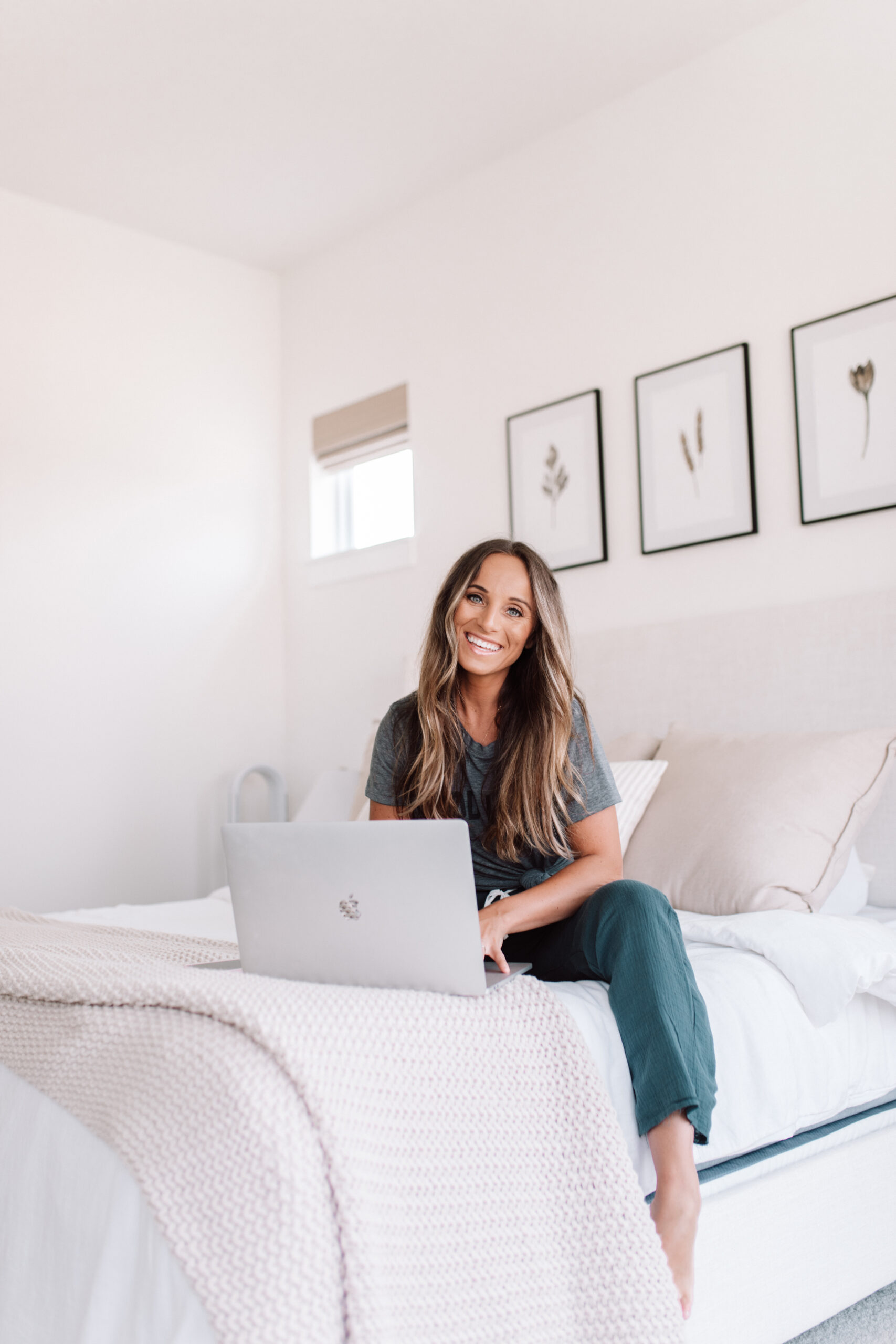 In this image, Jordan works from her laptop while sitting on her bed.